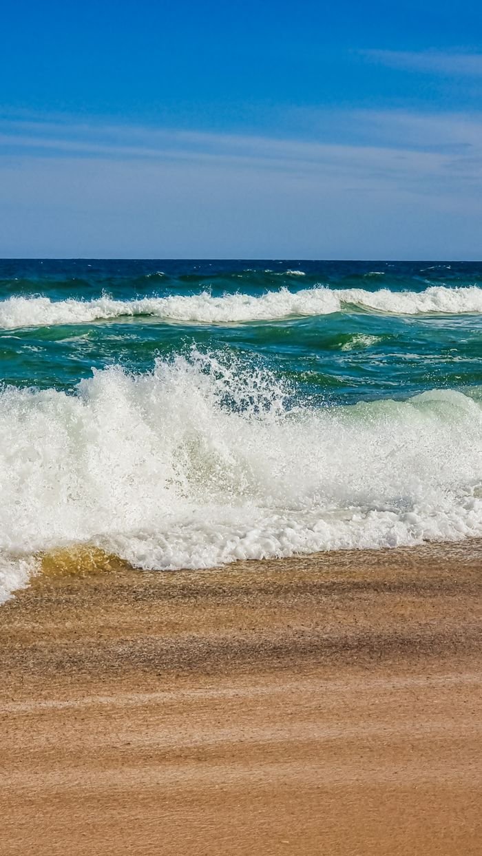 Captivating view of ocean waves crashing onto a sandy beach, capturing the essence of coastal serenity.